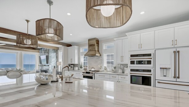 A modern kitchen with white cabinetry, a large island, and stainless steel appliances. - The Turtle's Palace- Oceanfront - Pool - Hot Tub - Dog Friendly (Surf City)