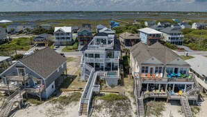 A coastal residential area with beachfront properties featuring balconies, wooden walkways, and beach chairs. - The Turtle's Palace- Oceanfront - Pool - Hot Tub - Dog Friendly (Surf City)