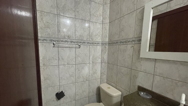 A bathroom with a toilet, sink, and mirror.
