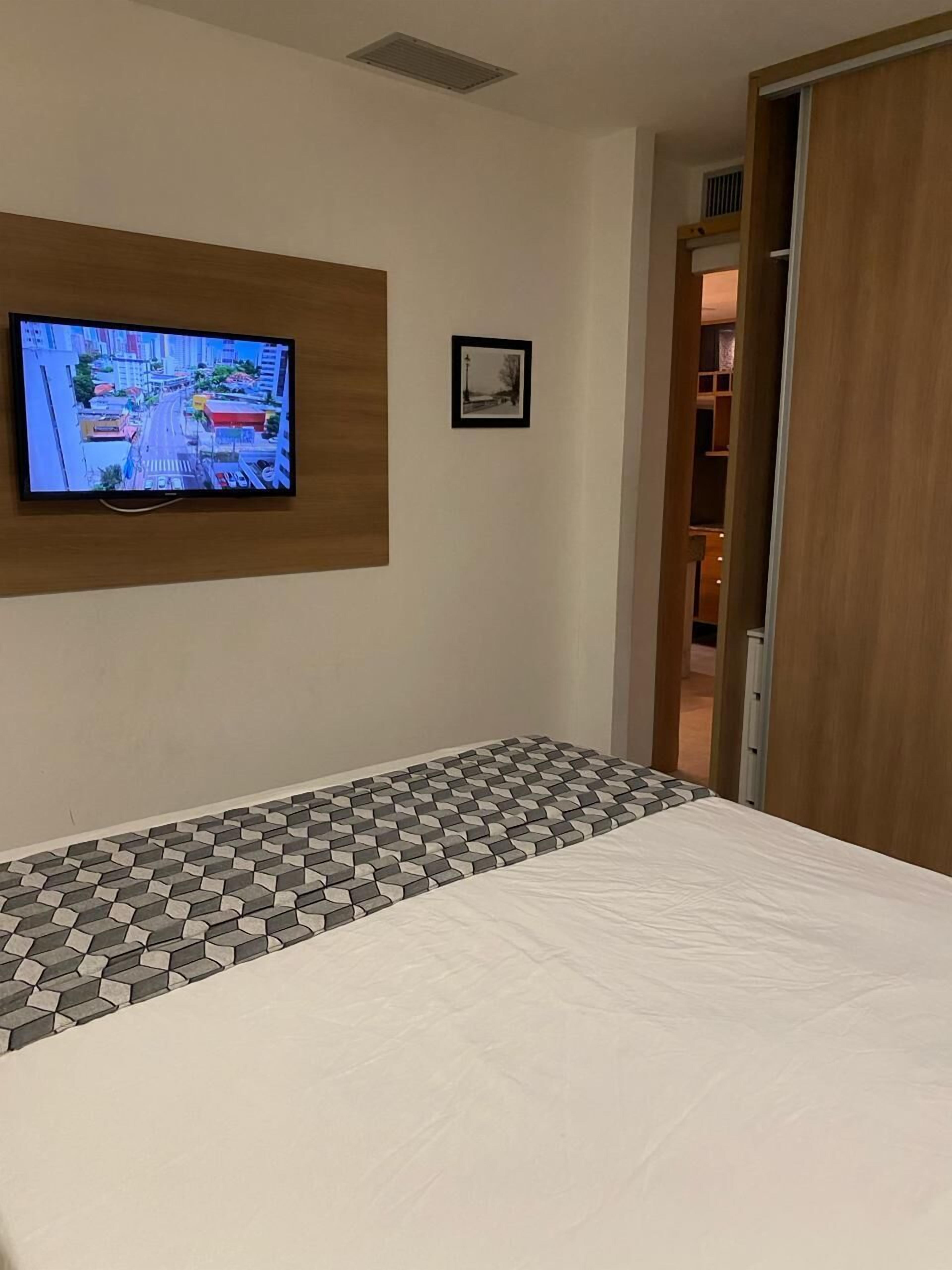 A hotel room with a bed, a television mounted on the wall, and a small framed picture.