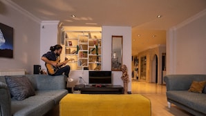 A living room with a sofa, a yellow ottoman, a TV, and a bookshelf. - Digital Nomad House (Istanbul)