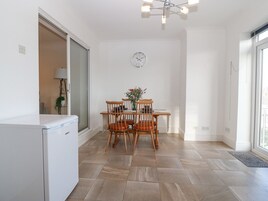 Una cocina moderna con lavavajillas integrado, una mesa de comedor con cuatro sillas de madera y un reloj de pared.