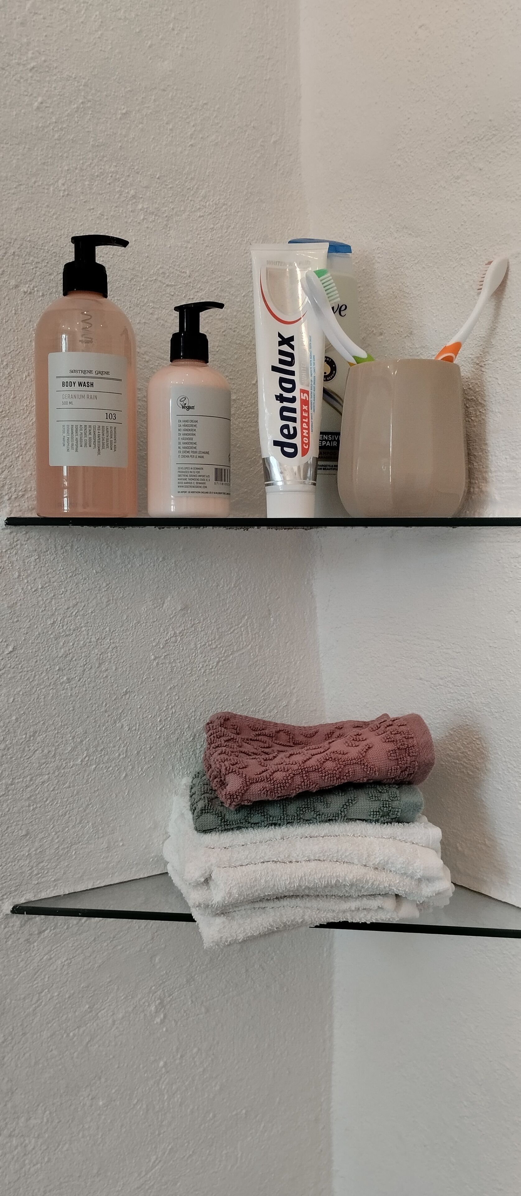 A bathroom shelf with body wash, toothpaste, and a toothbrush.