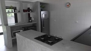 A modern kitchen with a central island, stainless steel appliances, and a tiled backsplash. - Casa em Maresias em Meio a Mata (Praia de Maresias São Sebastião)