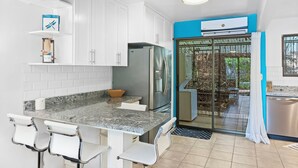 Une cuisine moderne avec des armoires blanches, un comptoir en granit et un réfrigérateur en acier inoxydable.