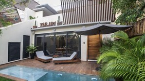 Un espace piscine extérieur moderne, doté de deux chaises longues et d’une terrasse en bois.