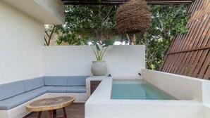 Une terrasse extérieure moderne dotée d’un espace salon intégré, d’une petite table ronde et d’un jacuzzi.