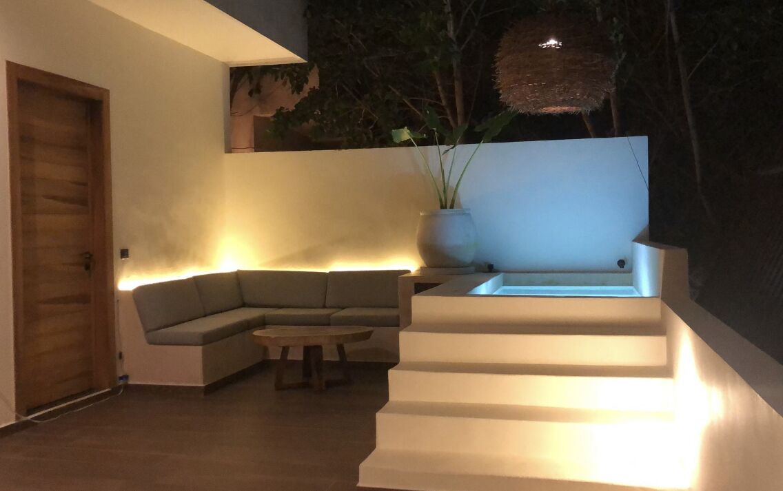 Una sala de estar moderna con un sofá modular, una mesa de centro y una escalera con iluminación integrada.