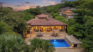 Uma casa com piscina, rodeada por vegetação exuberante e vários níveis.