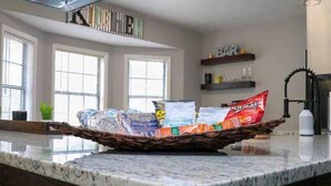 Un comptoir de cuisine sur lequel se trouve un panier en osier contenant divers en-cas emballés et une bouteille d’eau.