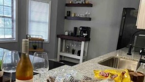 Une cuisine dotée d’un plan de travail en granit, d’une bouteille de vin, d’un panier de collations et d’une machine à café.