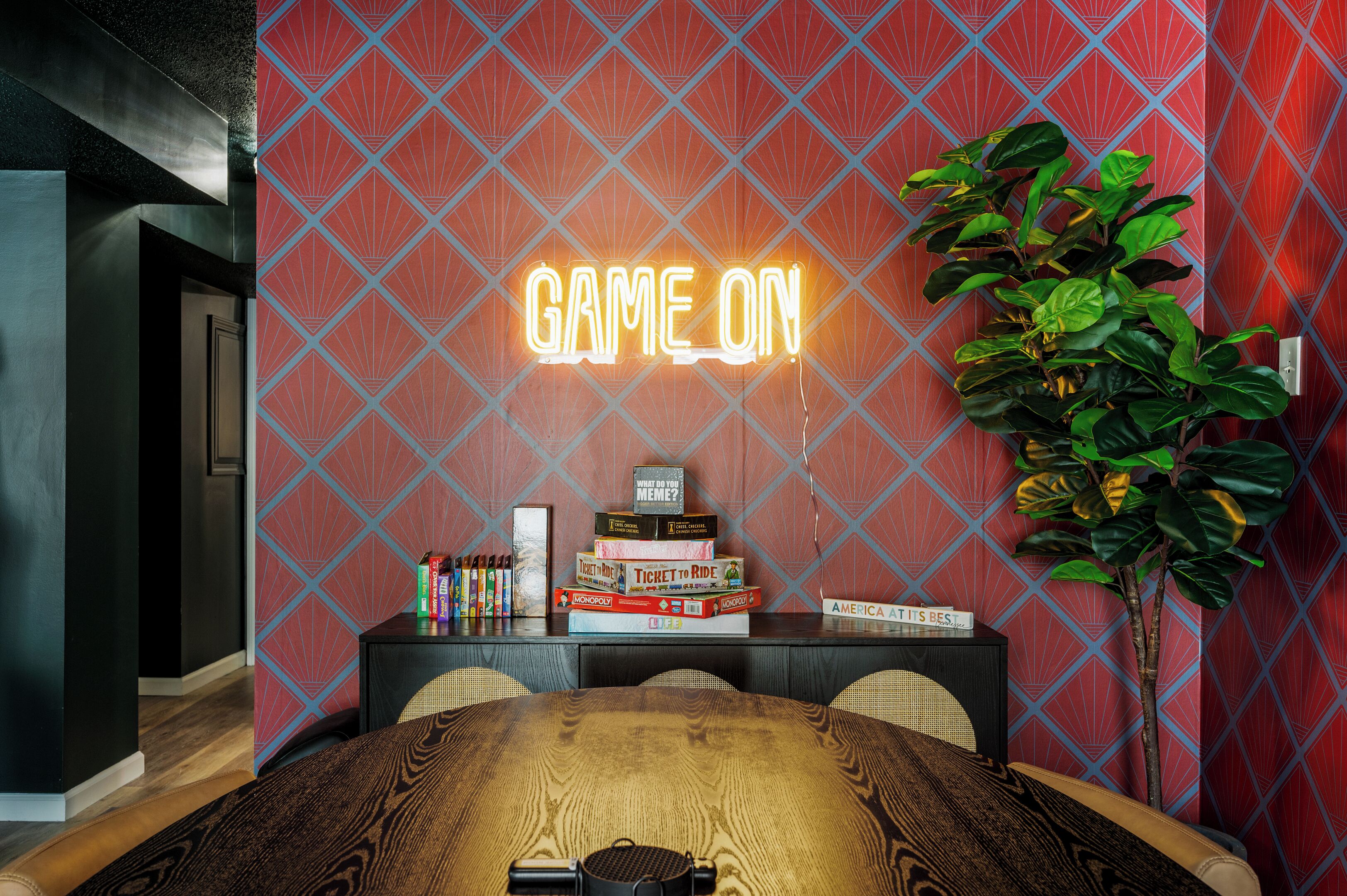 Ett rum med en neonskylt som visar texten ”GAME ON” ovanför en hylla med brädspel.
