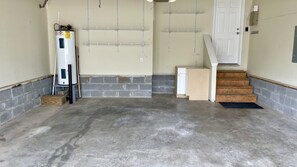 Utility space with a water heater, metal shelving, and staircase.