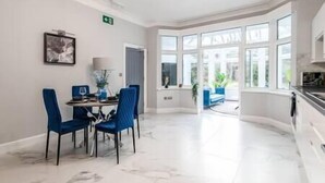 A bright dining area with a table and chairs, a window with a view, and a door leading outside.