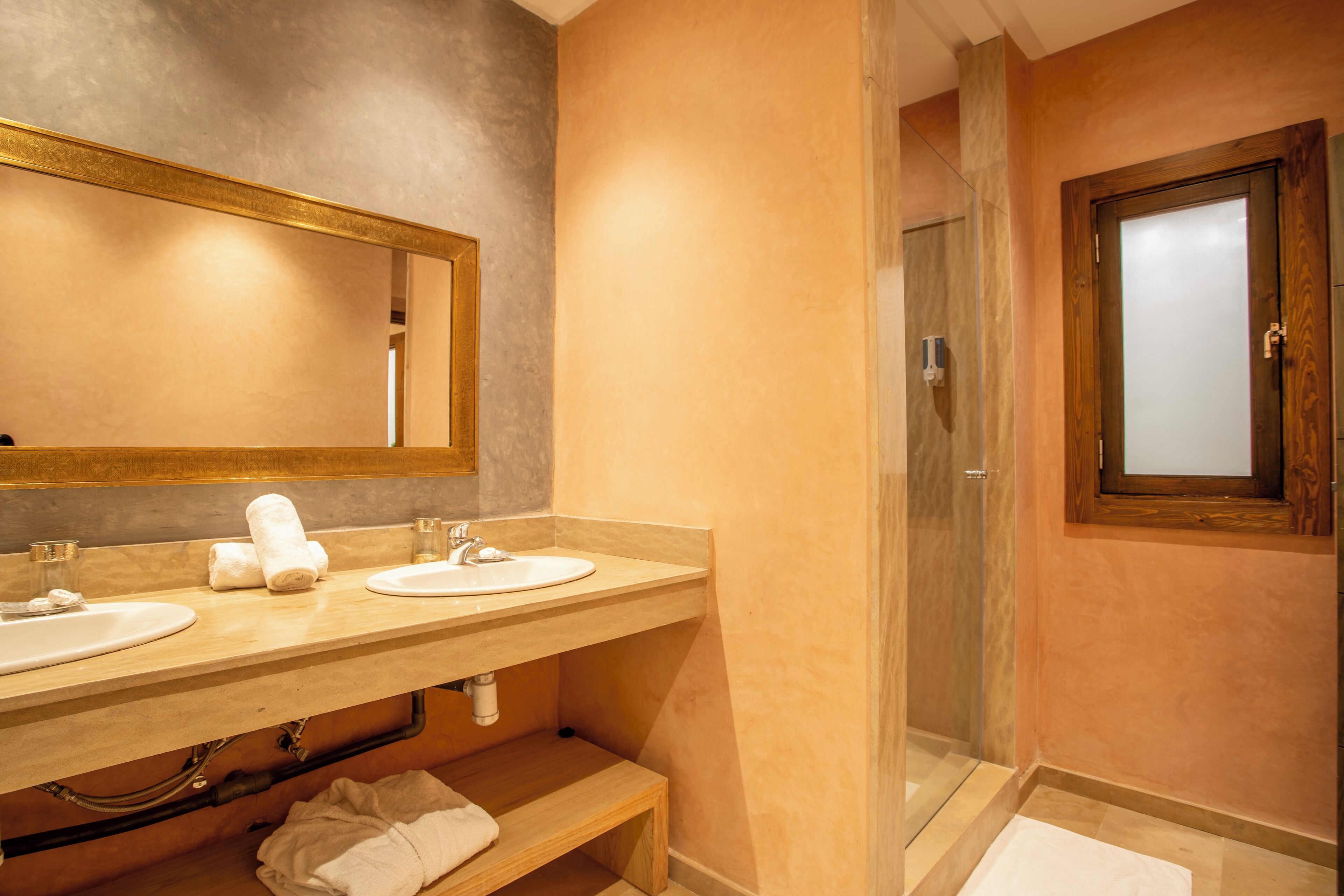 A bathroom with two sinks, a large mirror, and a shower.