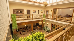 A multi-level hotel lobby with a glass ceiling, a central seating area, and a staircase.