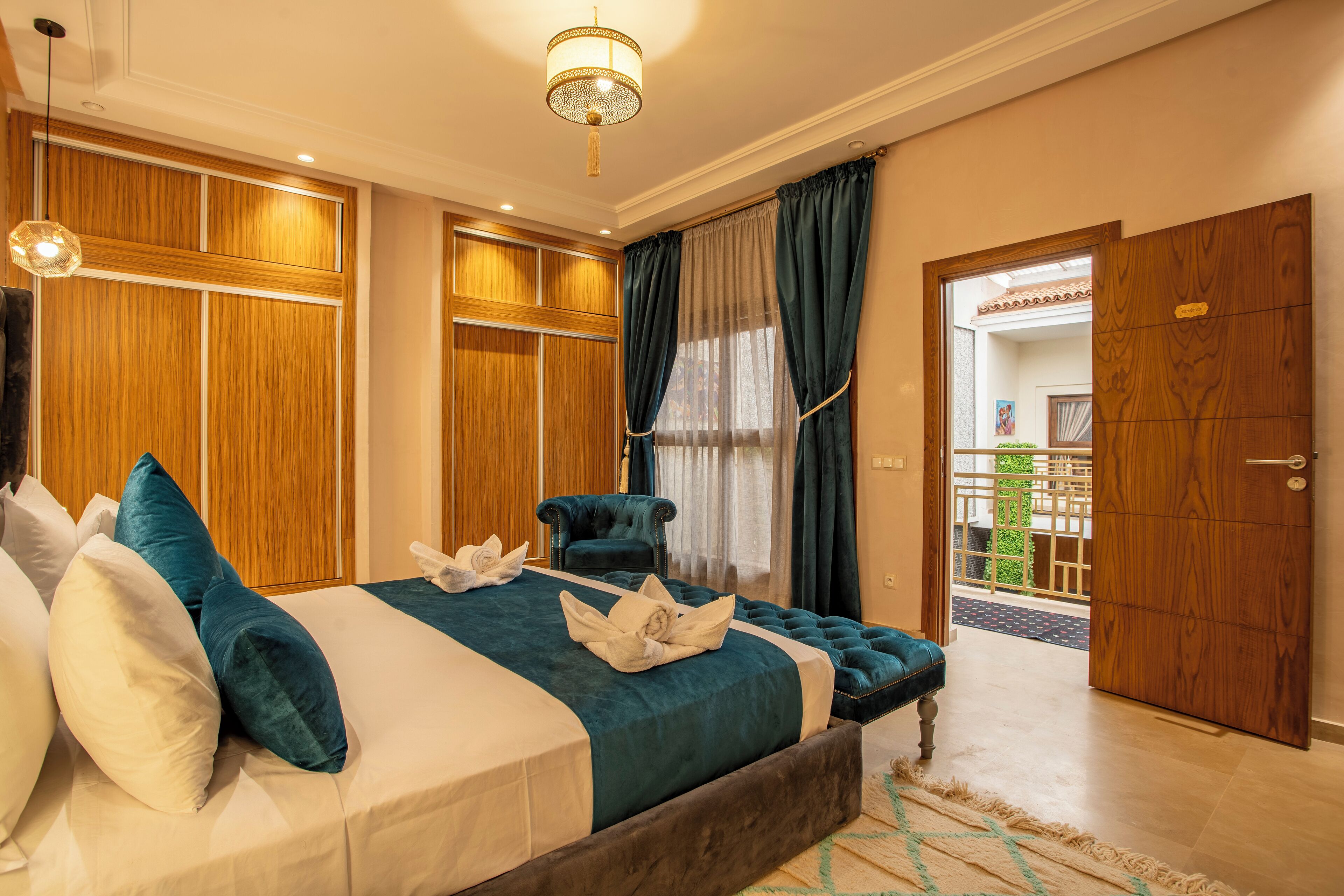 Habitación de hotel con una cama grande, armario de madera, zona de estar con una silla y vistas al exterior.