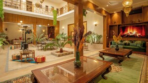 A spacious lobby with a high ceiling, a central fireplace, and multiple seating areas.