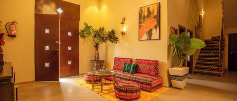 A lobby with a sofa set, a coffee table, a potted plant, and a staircase.