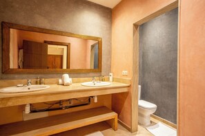 A bathroom with two sinks, a large mirror, and a toilet.
