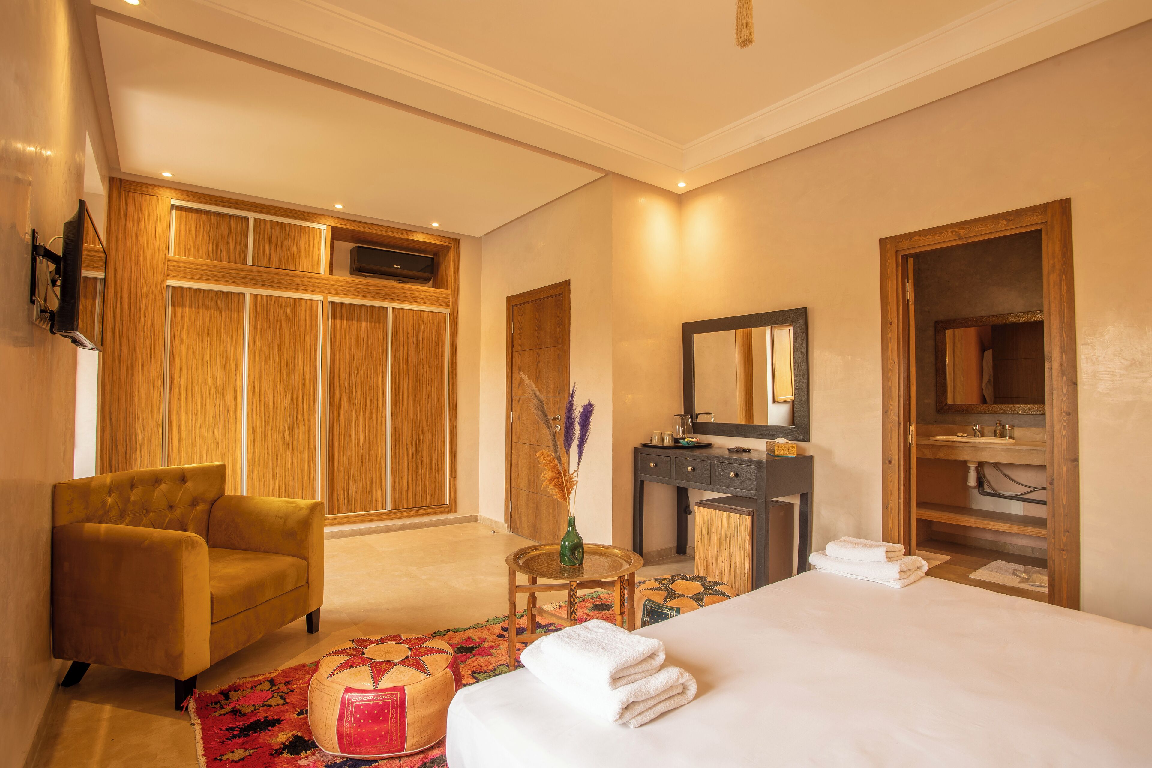 Habitación de hotel con cama, una silla, tocador y armario.