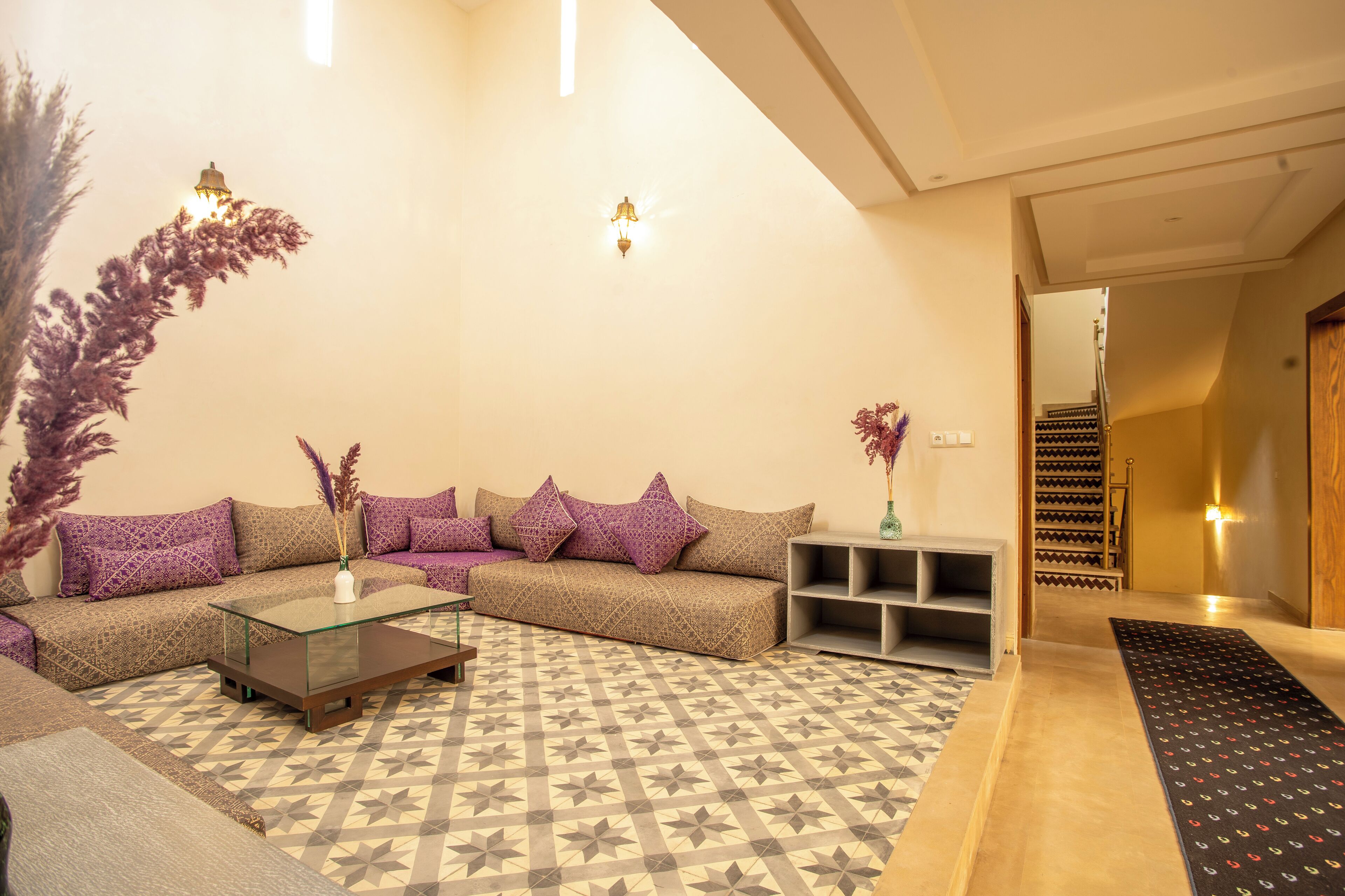 Sala de estar com sofá, mesa de centro, tapete estampado e plantas decorativas.