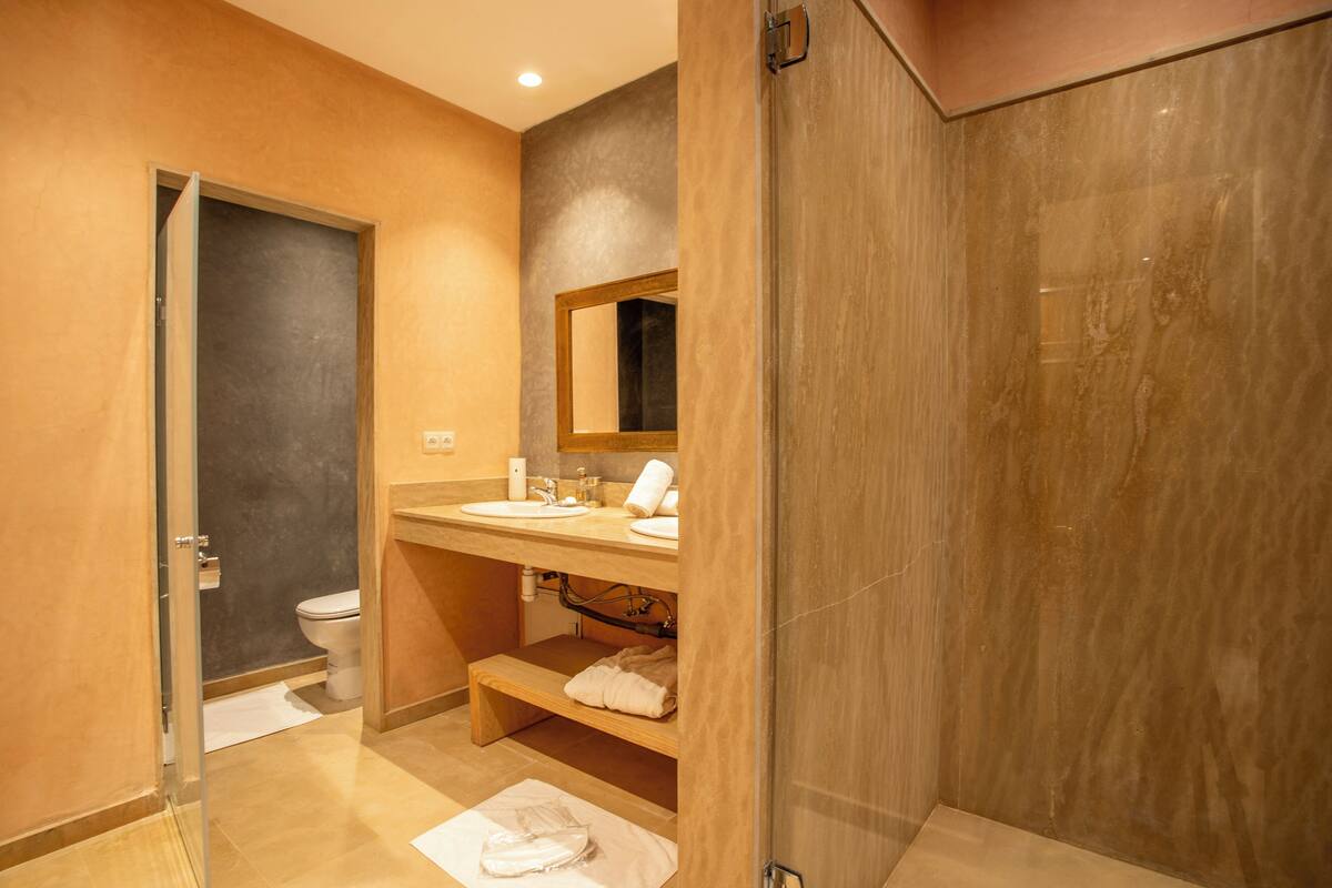 A modern bathroom with a glass shower enclosure, a wooden vanity, and a toilet.