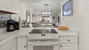 A modern kitchen with white cabinetry, a built-in stove, and a coffee maker. - Sea La Vie: 2Bed Gulf-Adjacent Condo - by SkyRun Anna Maria (Bradenton Beach)