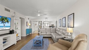 A modern living room with a television, sofa, and coffee table. - Sea La Vie: 2Bed Gulf-Adjacent Condo - by SkyRun Anna Maria (Bradenton Beach)