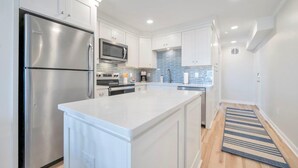 A modern kitchen with white cabinetry, stainless steel appliances, and a blue-tiled backsplash. - Oceanfront in Ocean Isle Beach! "C2 Shining Sea" - 3 bed 2 bath Condo - Sleeps 8 (Ocean Isle Beach)