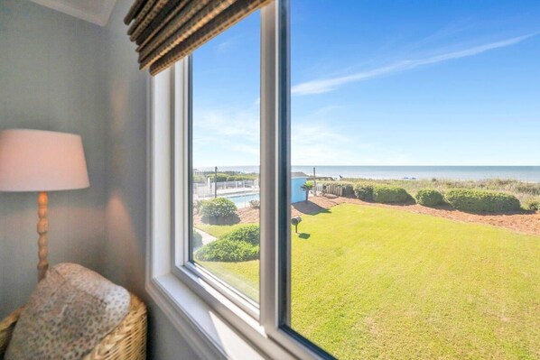 A room with a large window overlooking a well-maintained lawn and a body of water. - Oceanfront in Ocean Isle Beach! "C2 Shining Sea" - 3 bed 2 bath Condo - Sleeps 8 (Ocean Isle Beach)