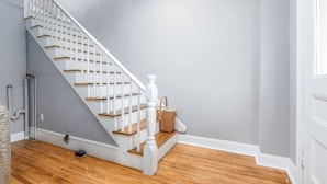 A staircase with white railings and wooden steps, leading to a landing with a basket.
