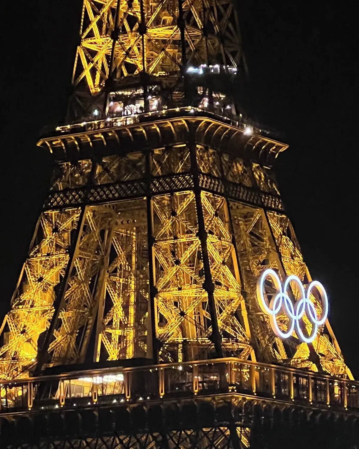 The Eiffel Tower at night with the Olympic rings illuminated on its side.