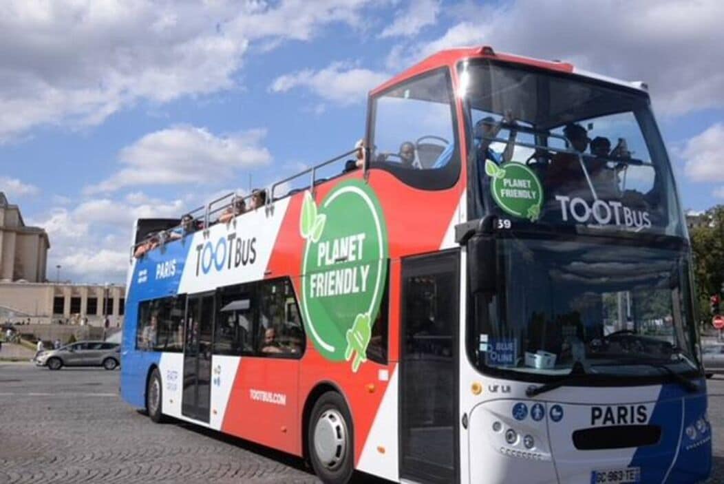 A double-decker bus with "TOOTBUS" and "PLANET FRIENDLY" logos, parked in an urban setting.