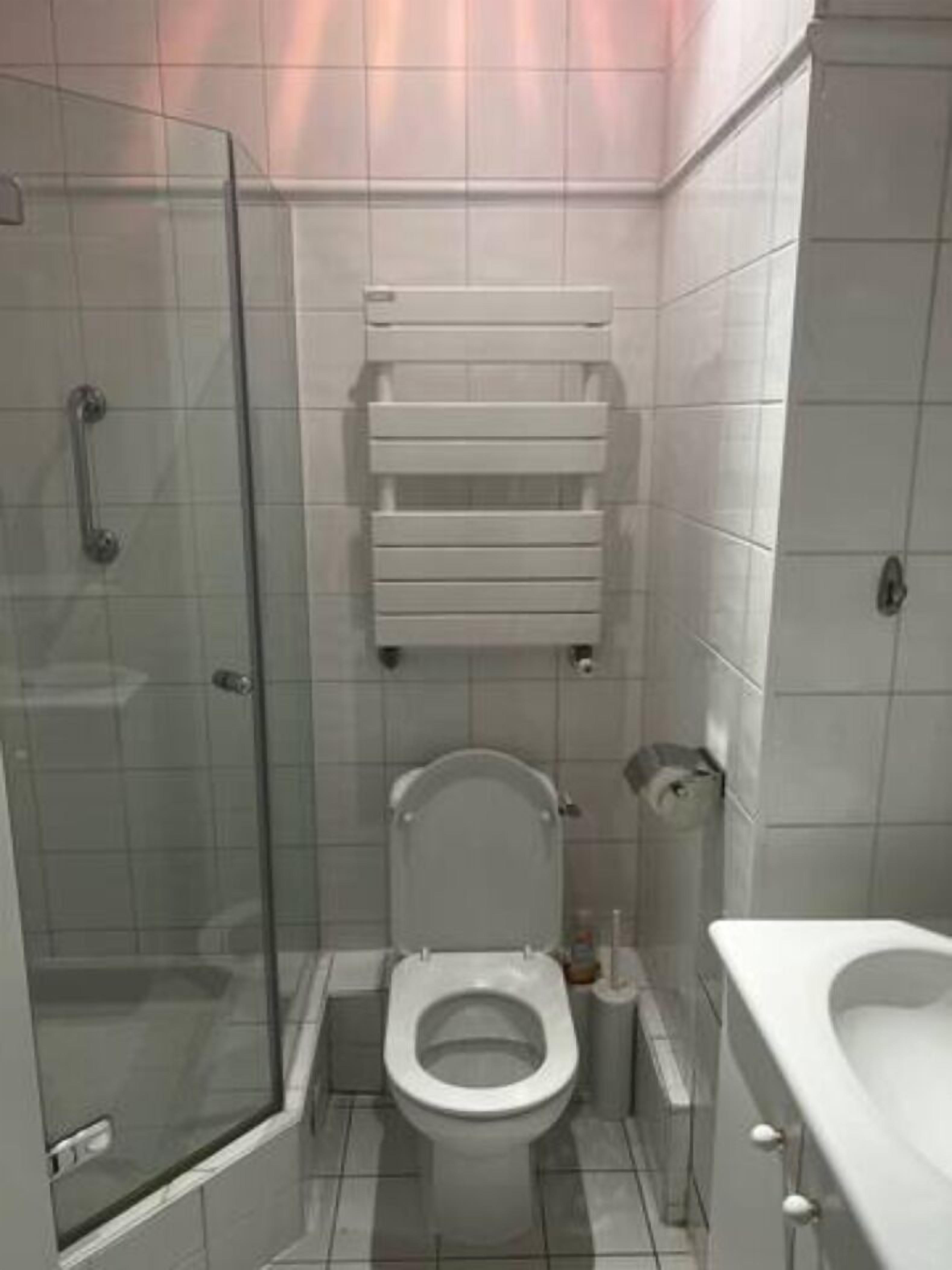 Pieni, moderni kylpyhuone, jossa on lasiseinäinen suihkukaappi, wc ja pesuallas.