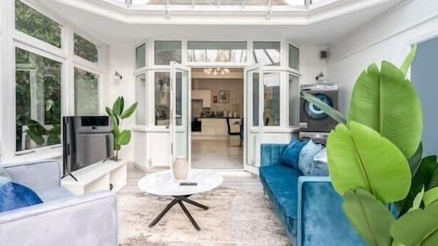 A modern living room with a blue sofa, a round coffee table, and a TV. - Modern studio near Wembley #2 (Harrow)