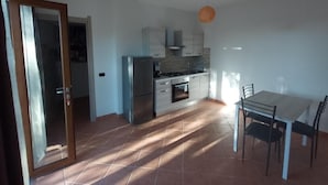 A kitchen with a dining table and chairs, a stove, oven, and cabinets. - agriturismo tres montes (Sorso)