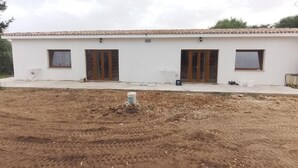 A white building with a tiled roof, three wooden doors, and a small window on the left. - agriturismo tres montes (Sorso)