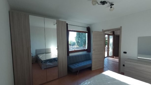 A bedroom with a bed, a wardrobe, a seating area, and a TV. - agriturismo tres montes (Sorso)