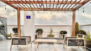 A covered outdoor seating area with wooden furniture and string lights. - Private apartement with ocean view (La Perla callao)