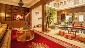 A spacious living area with a large TV, wooden furniture, a red carpet, and a pool. - Riad kenza (Marrakech)