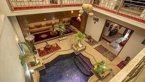 A luxurious indoor pool area with a seating area, a hot tub, and a balcony with a red carpet. - Riad kenza (Marrakech)