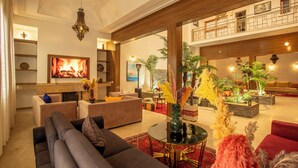 A spacious living area with a fireplace, comfortable seating, and decorative plants. - Riad kenza (Marrakech)