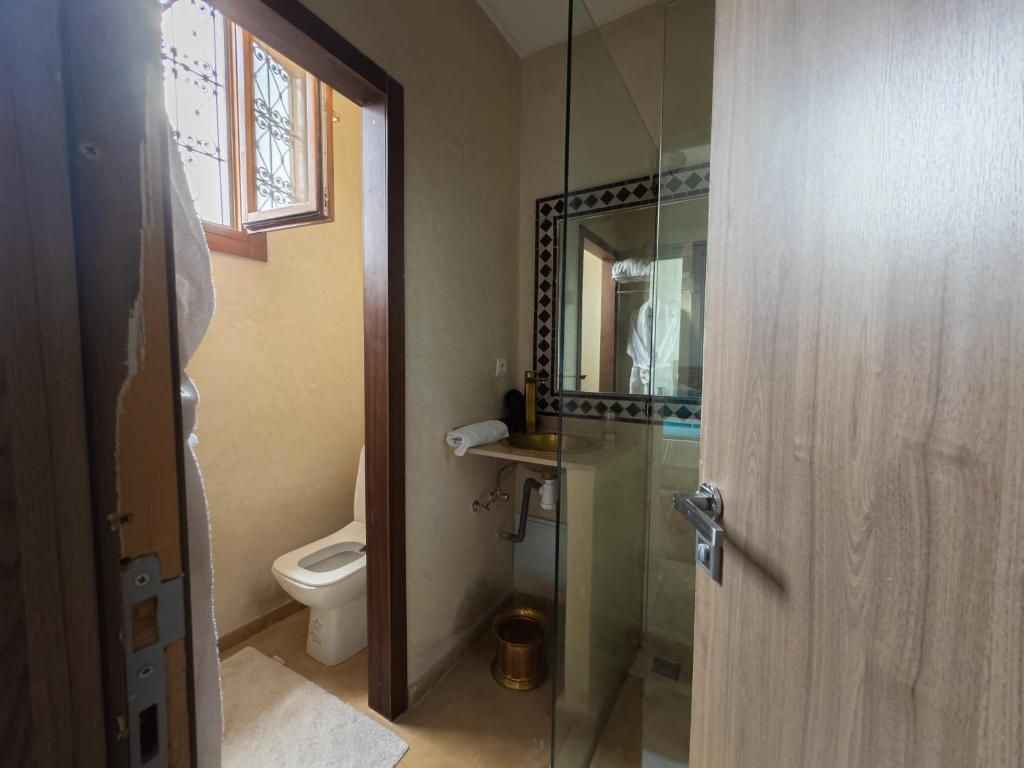 Une salle de bain équipée de toilettes, d’un lavabo et d’une douche à parois en verre.
