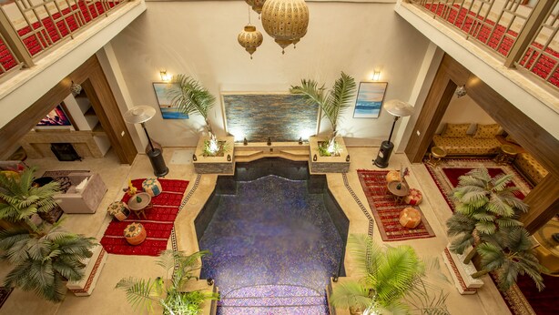 A spacious lobby with a central fountain, red carpets, and decorative plants. - Riad kenza (Marrakech)