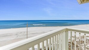 A beach view from a balcony with a railing, clear sky, and calm sea. - Beach House - Anchors Aweigh by PHG (Panama City Beach)