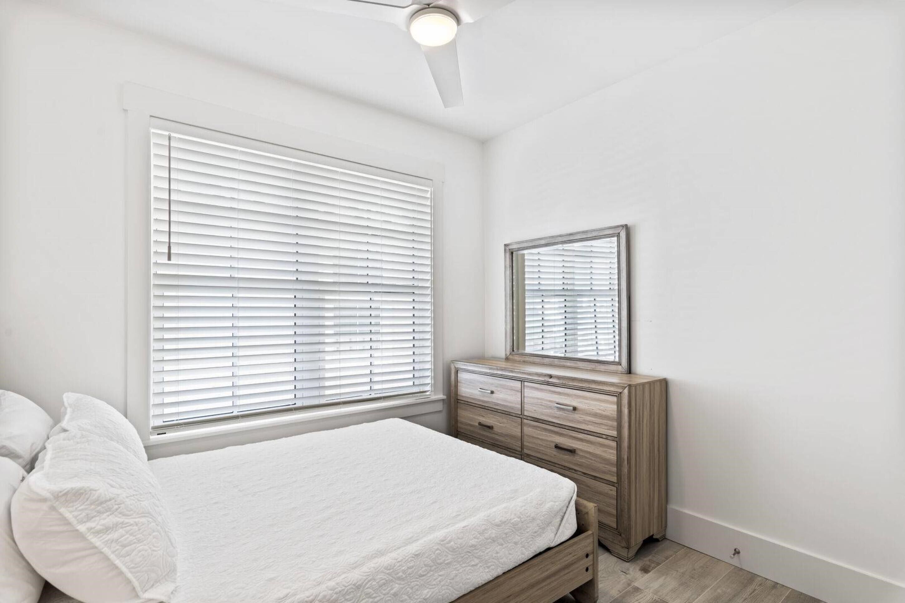 Un dormitorio con cama, cómoda, espejo y ventilador de techo.