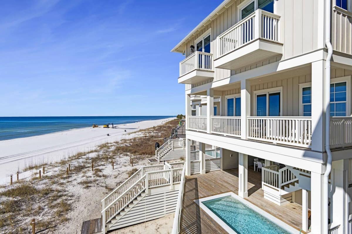 A beachfront property with a pool, multiple balconies, and a beach view.