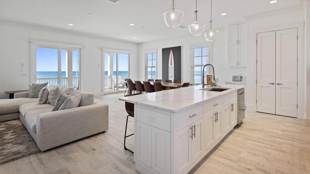 A spacious living area with a large island, a dining table, and a view of the ocean. - Beach House - Anchors Aweigh by PHG (Panama City Beach)