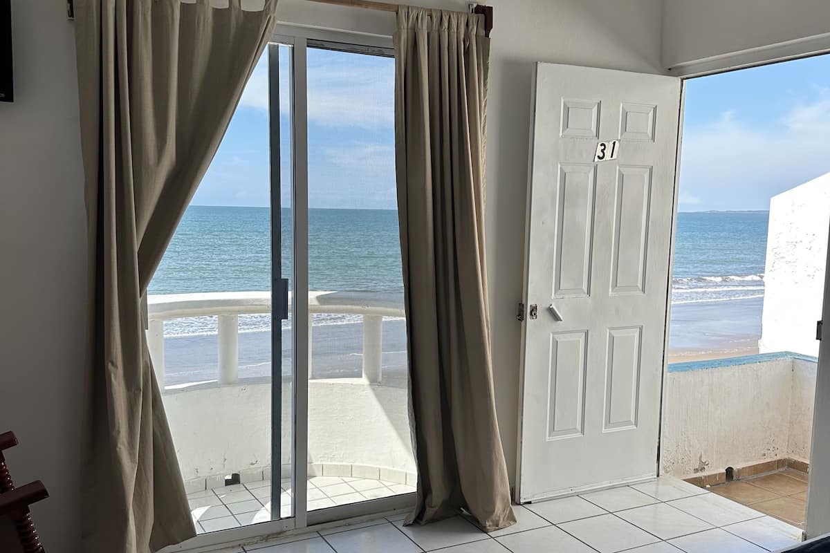 Une chambre avec un lit, une vue sur la plage et une porte portant le numéro « 31 ».